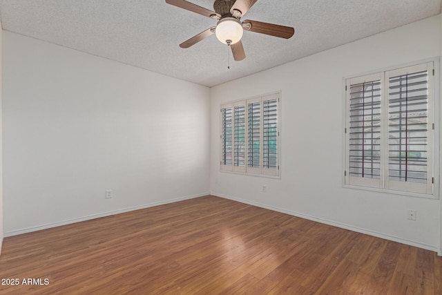 empty room featuring ceiling fan, a textured ceiling, baseboards, and wood finished floors