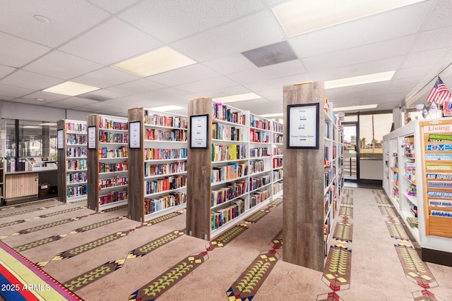 miscellaneous room with a paneled ceiling and wall of books