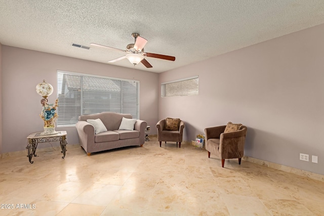 sitting room with a textured ceiling, baseboards, visible vents, and a ceiling fan