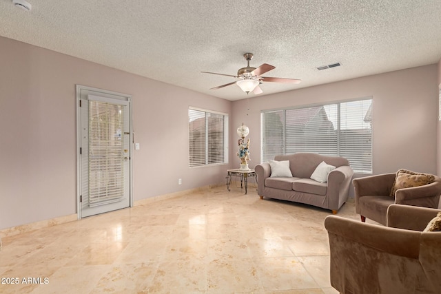 living area featuring ceiling fan, a textured ceiling, visible vents, and baseboards