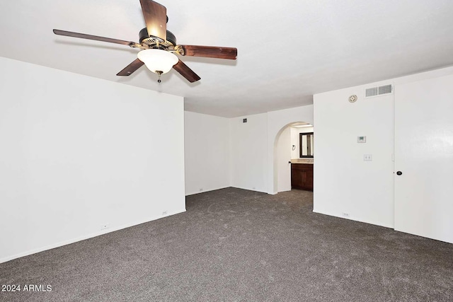 spare room with ceiling fan and dark colored carpet