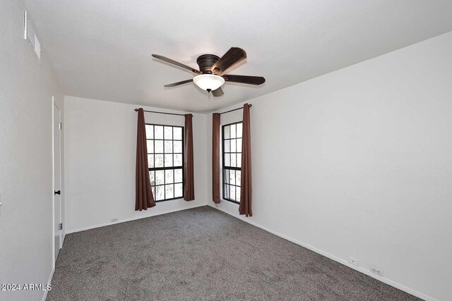 empty room featuring ceiling fan and dark colored carpet