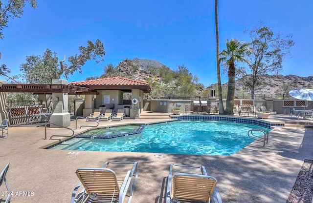 view of swimming pool featuring a hot tub, a mountain view, and a patio area