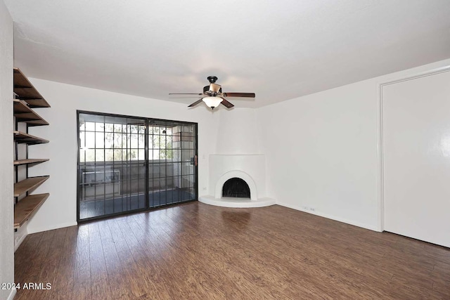 unfurnished living room featuring a large fireplace, ceiling fan, and dark hardwood / wood-style flooring