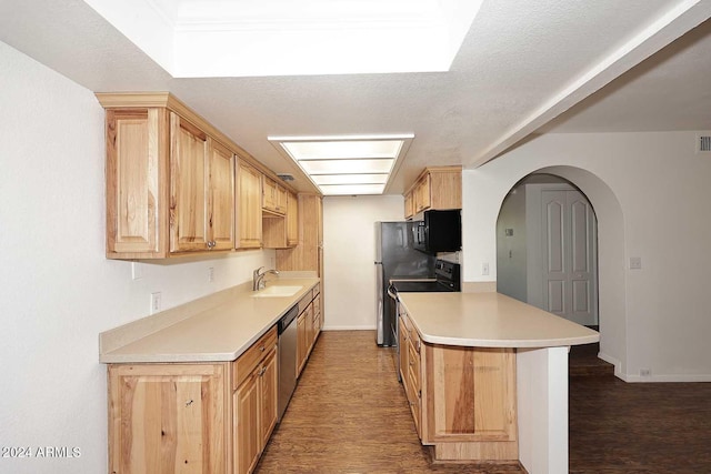 kitchen with dark wood-type flooring, kitchen peninsula, black appliances, light brown cabinetry, and sink