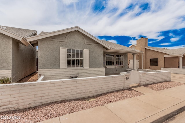 2929 E Broadway Rd Unit 30, Mesa, AZ 85204 - view of front facade with a fenced front yard, stucco siding, a chimney, and a gate
