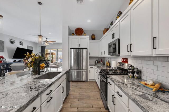 kitchen with hanging light fixtures, white cabinets, sink, and stainless steel appliances