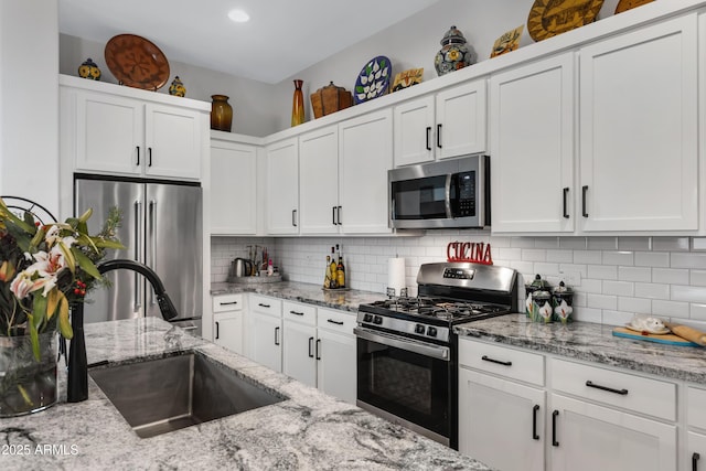 kitchen featuring tasteful backsplash, appliances with stainless steel finishes, light stone counters, and white cabinetry