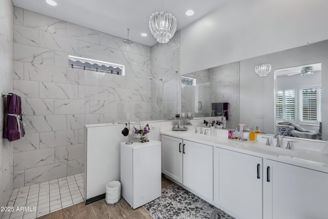 bathroom with vanity, hardwood / wood-style flooring, an inviting chandelier, and a tile shower