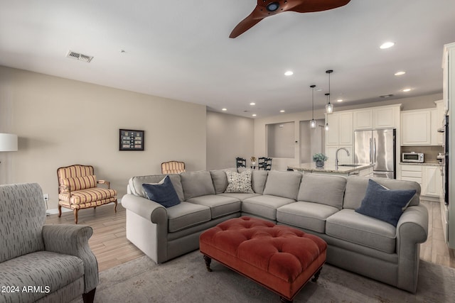 living room with ceiling fan, sink, and light hardwood / wood-style floors