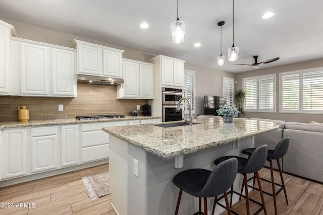 kitchen with white cabinets, a center island with sink, and ceiling fan