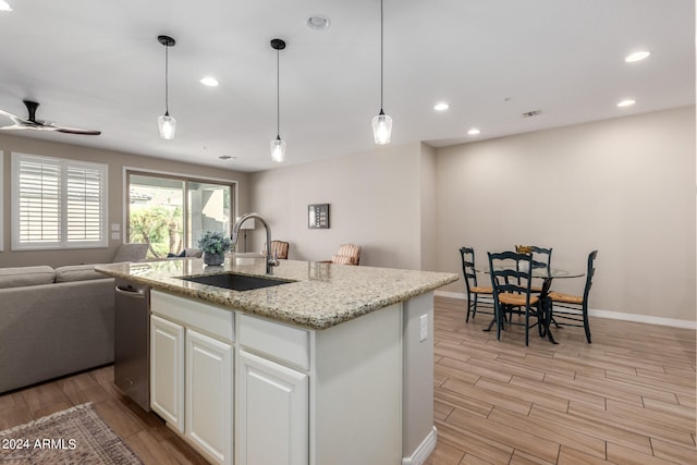 kitchen featuring white cabinets, a kitchen island with sink, sink, and light wood-type flooring