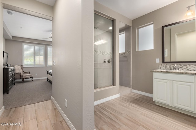 bathroom with ceiling fan, wood-type flooring, tiled shower, backsplash, and vanity