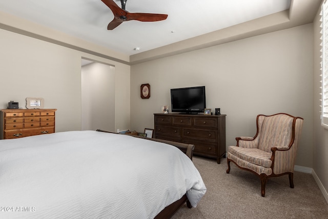 bedroom with light carpet, ceiling fan, and a raised ceiling