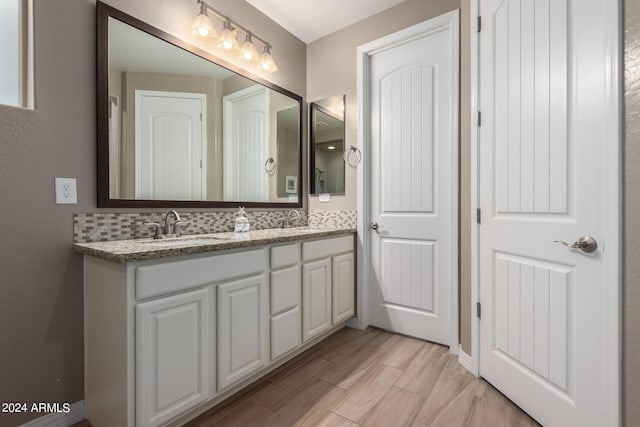 bathroom with wood-type flooring, vanity, and decorative backsplash