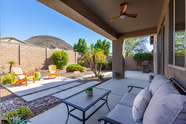 view of patio with an outdoor living space, area for grilling, a mountain view, and ceiling fan