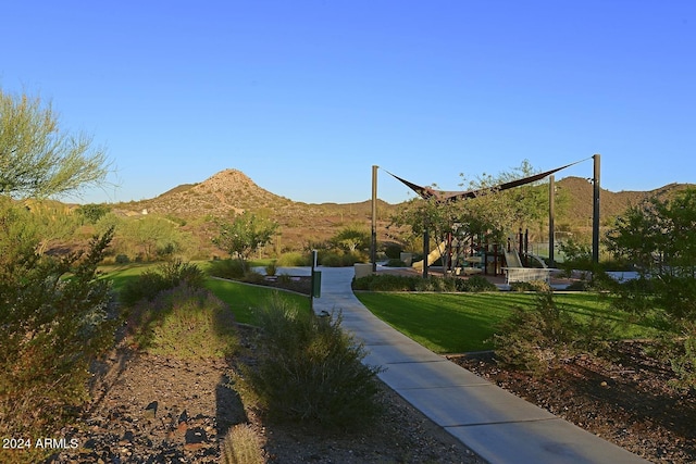 view of property's community with a mountain view and a lawn