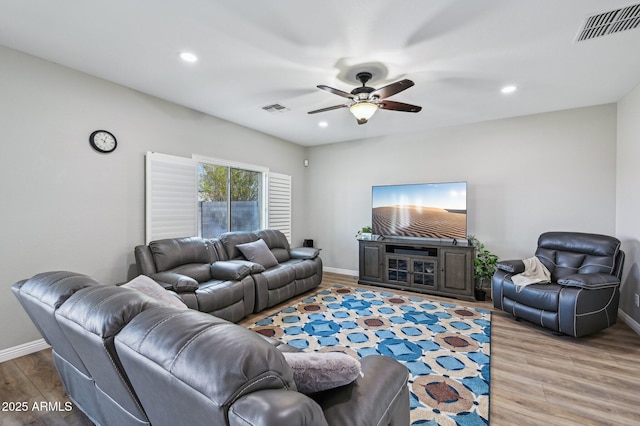 living area with a ceiling fan, wood finished floors, visible vents, and baseboards