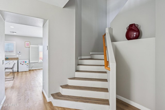 staircase featuring baseboards and wood finished floors