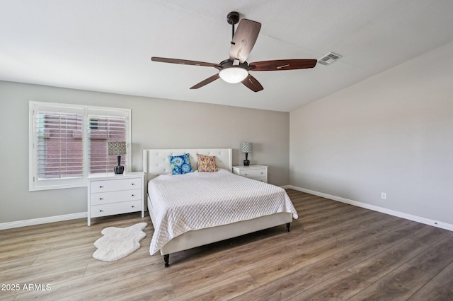 bedroom with visible vents, baseboards, and wood finished floors