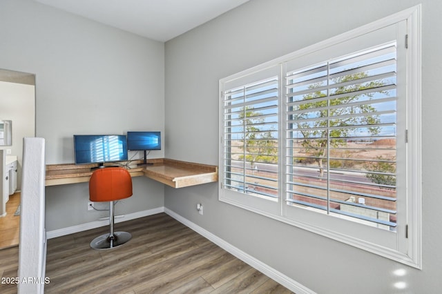 home office with baseboards, wood finished floors, and built in desk