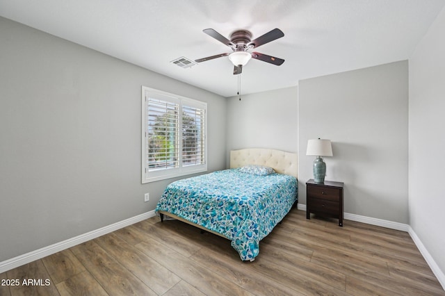 bedroom with visible vents, baseboards, wood finished floors, and a ceiling fan