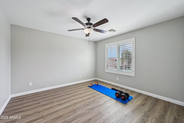 exercise area featuring visible vents, baseboards, a ceiling fan, and wood finished floors