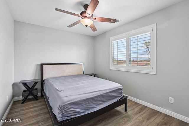 bedroom with dark wood-style floors, visible vents, ceiling fan, and baseboards