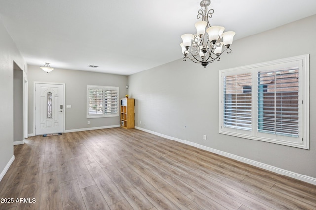 interior space featuring baseboards, wood finished floors, visible vents, and a chandelier