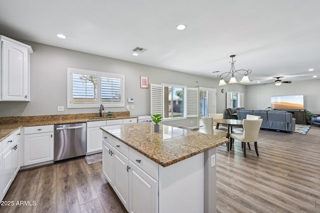 kitchen with visible vents, open floor plan, stainless steel dishwasher, wood finished floors, and a sink