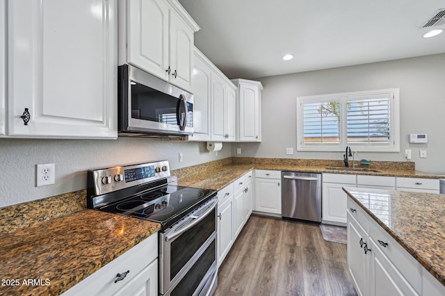 kitchen with dark wood-style floors, visible vents, a sink, appliances with stainless steel finishes, and white cabinetry