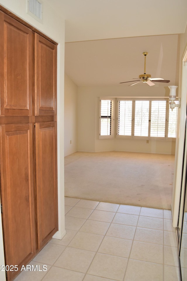 empty room featuring light colored carpet, ceiling fan, and a healthy amount of sunlight