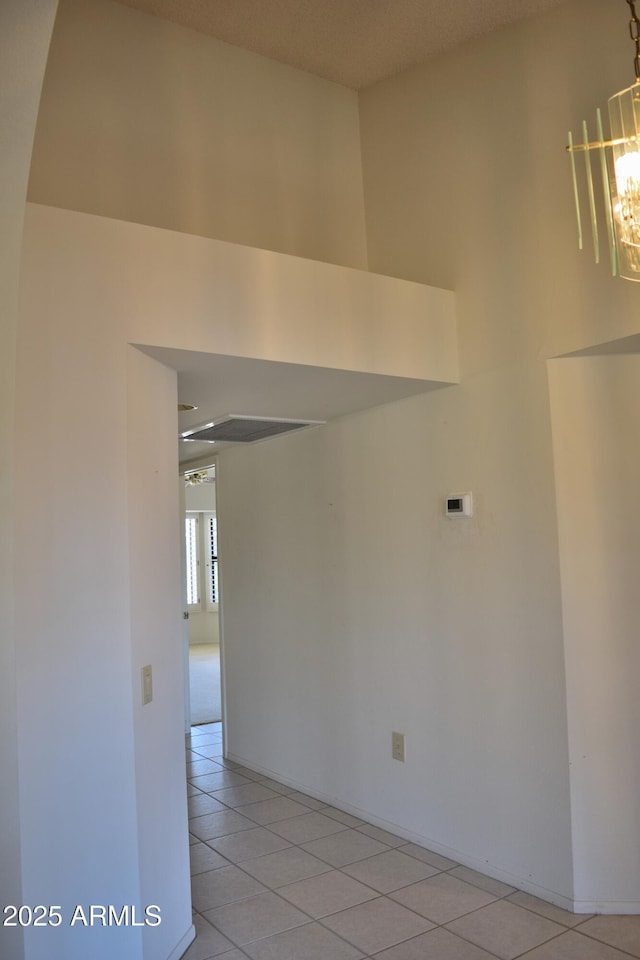 tiled spare room with a towering ceiling