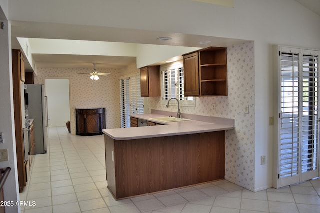 kitchen featuring kitchen peninsula, light tile patterned floors, ceiling fan, and sink