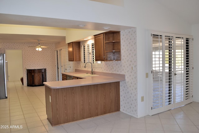 kitchen featuring stainless steel refrigerator, ceiling fan, sink, kitchen peninsula, and light tile patterned floors