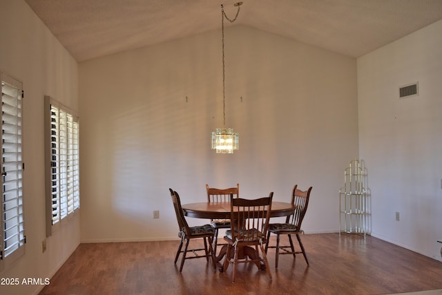 dining space with a chandelier, hardwood / wood-style floors, and lofted ceiling