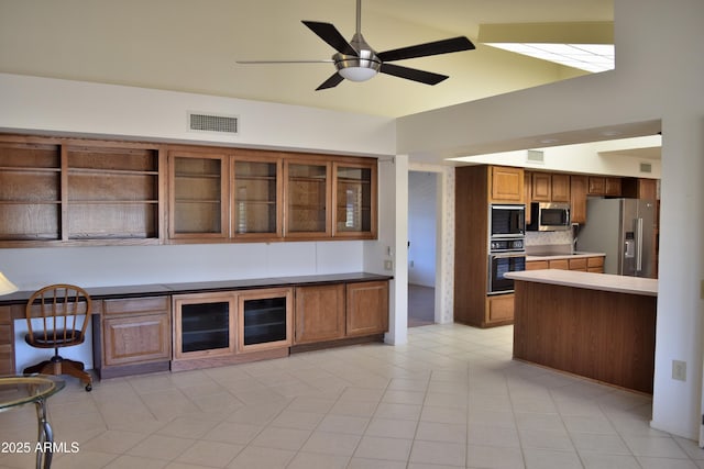 kitchen with ceiling fan, kitchen peninsula, decorative backsplash, light tile patterned floors, and black appliances