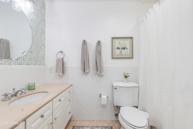 full bath with tile patterned floors, wainscoting, toilet, and vanity