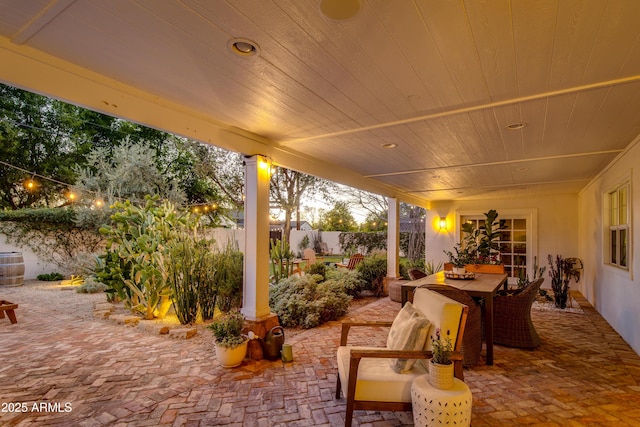 patio terrace at dusk with outdoor dining space and fence