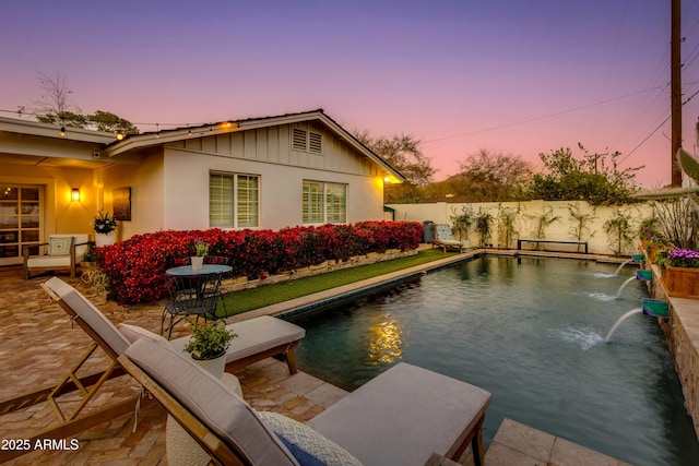 pool at dusk with a patio area, a fenced backyard, and a fenced in pool