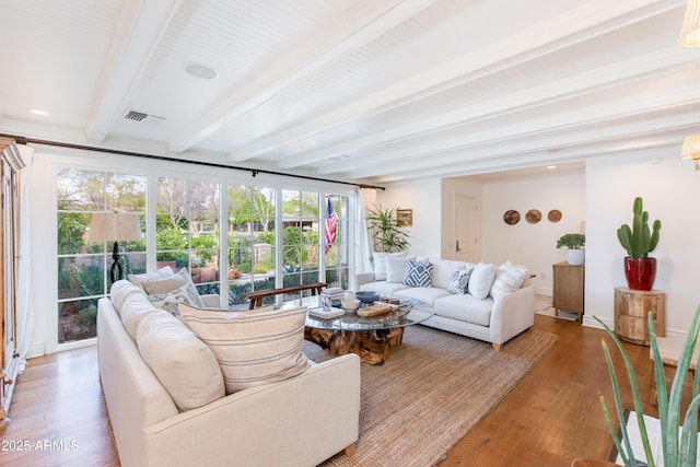 living room featuring visible vents, beam ceiling, and light wood-style flooring