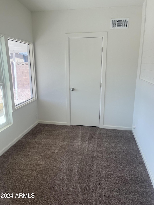 unfurnished room with dark carpet