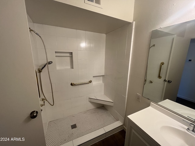 bathroom featuring vanity, wood-type flooring, and tiled shower