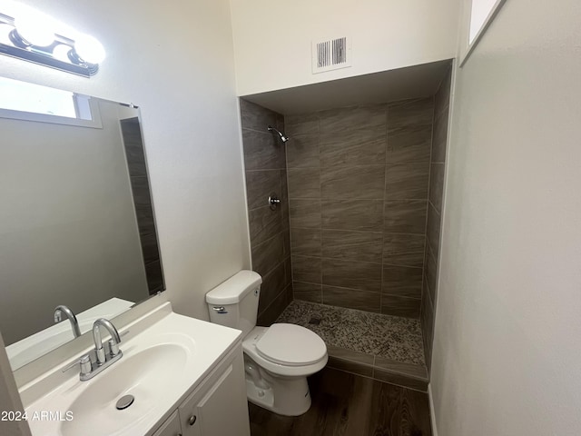 bathroom featuring vanity, toilet, wood-type flooring, and a tile shower