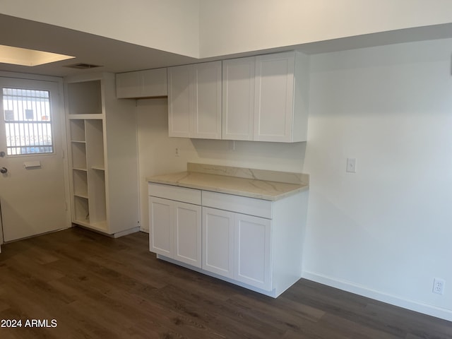 kitchen with dark hardwood / wood-style floors, light stone countertops, and white cabinetry