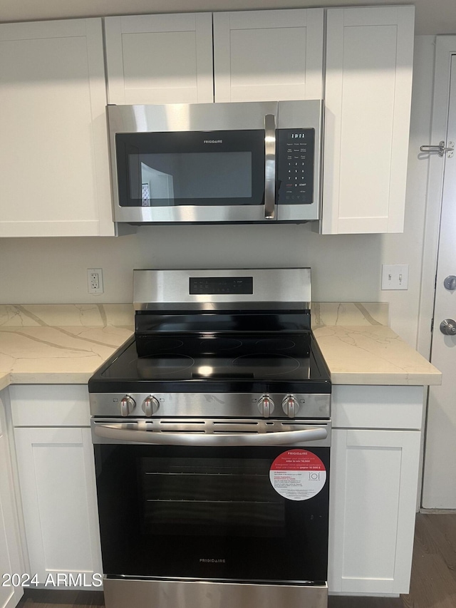 kitchen with light stone countertops, white cabinets, and appliances with stainless steel finishes