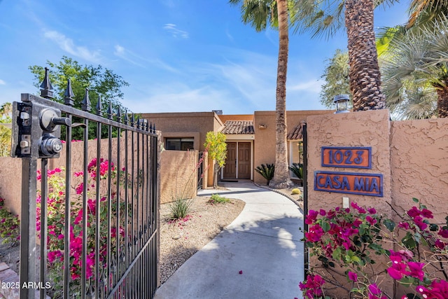 view of front of house with fence, stucco siding, and a gate