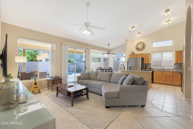 living room featuring ceiling fan, light tile patterned flooring, a wealth of natural light, and vaulted ceiling