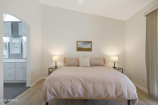 bedroom featuring light wood-type flooring, ceiling fan, lofted ceiling, and connected bathroom