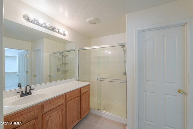 bathroom with a textured ceiling, vanity, and walk in shower